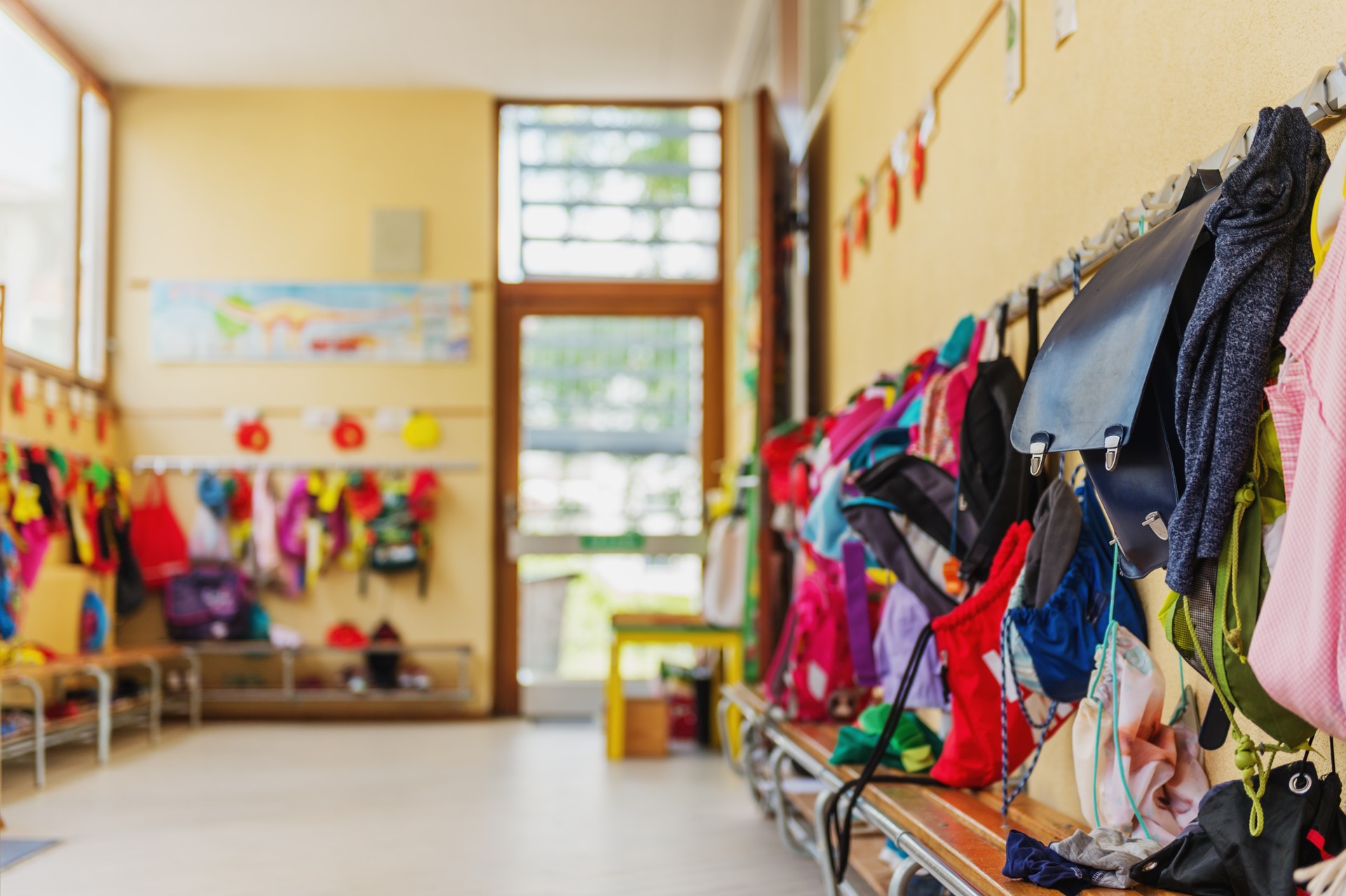 Empty hallway in the school, backpacks and bags on hooks, bright recreation room