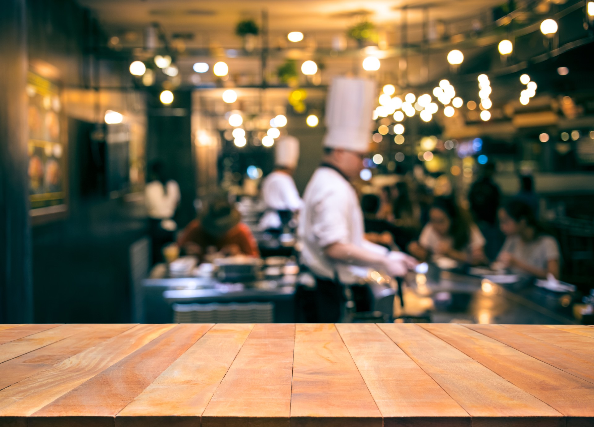 Wood table top with blur chef cooking in bar restaurant